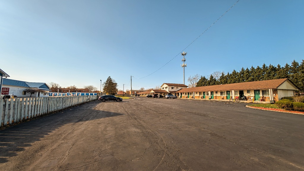 Delta Motel exterior in Bay City Michigan — spacious parking lot, motel rooms, and clear blue sky