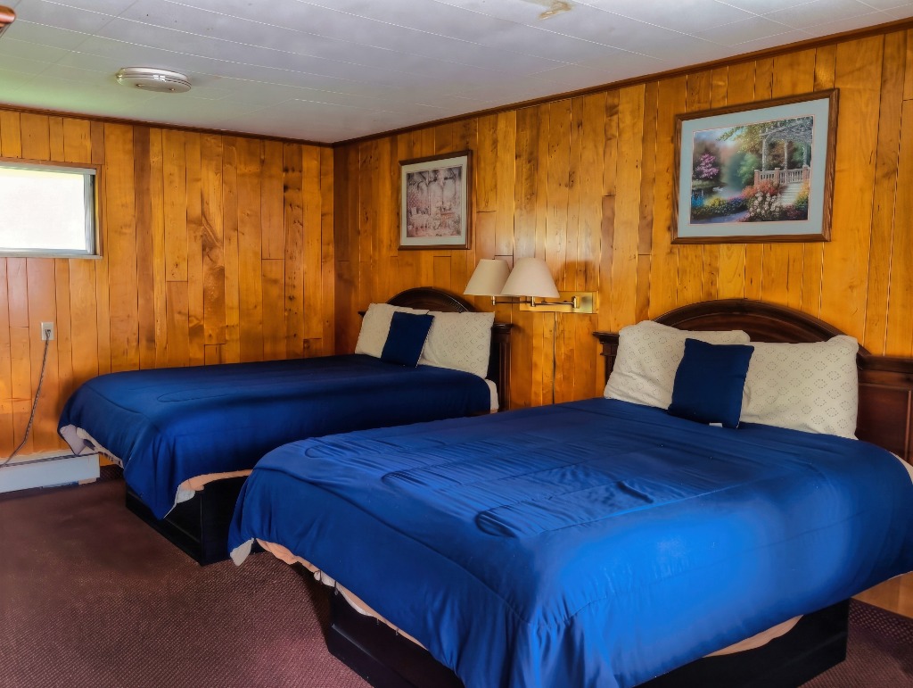Delta Motel double queen room featuring wood panel wall and blue bed covers