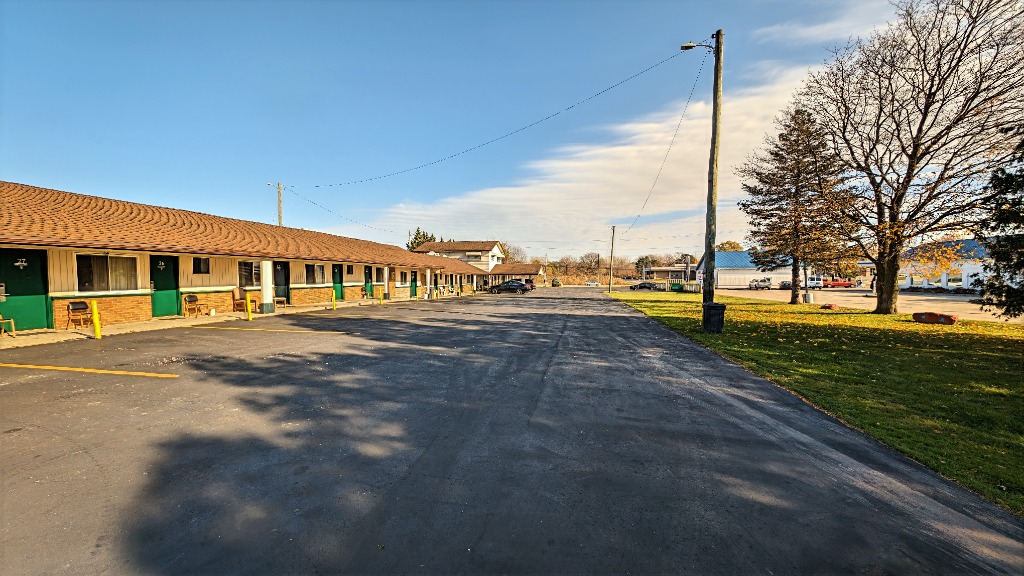 Delta Motel building front walkway with green room doors, lawn, and parking area